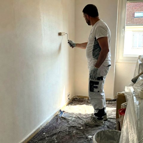 Artisan Hservices75 en train de peindre un mur lors d'une rénovation d'appartement à Paris
