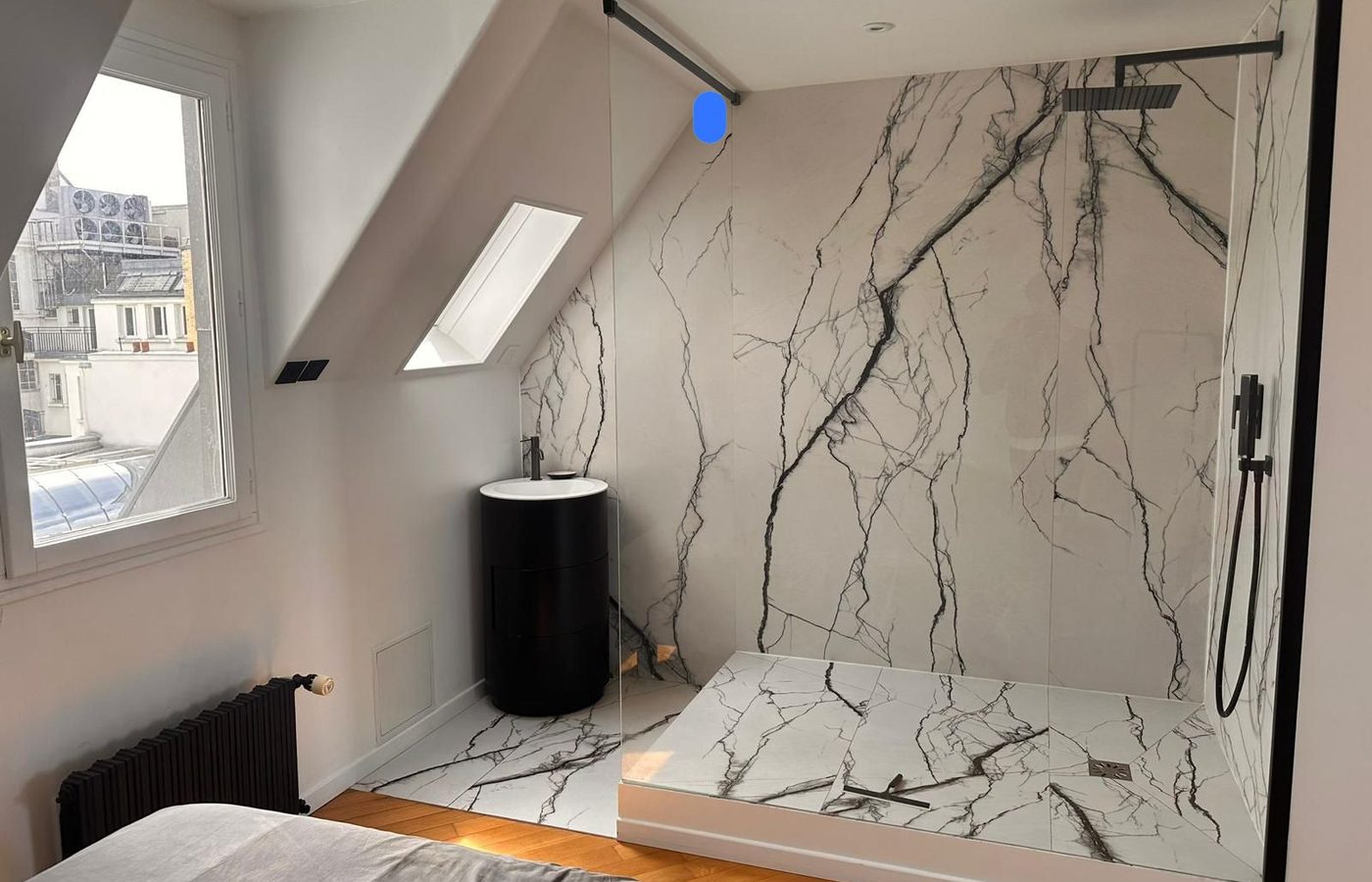 Salle de bain mansardée avec douche italienne en marbre et robinetterie noire mate